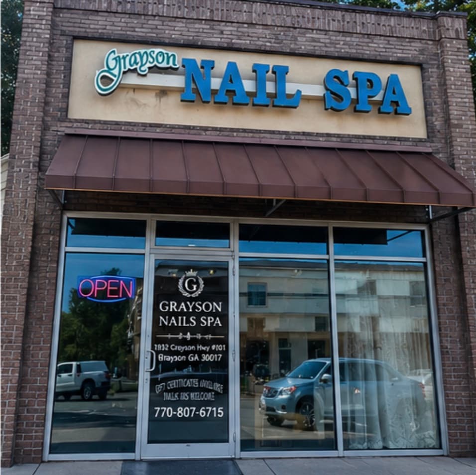 The salon from the street: a brick storefront on Grayson Highway with a blue Grayson Nail Spa sign above a brown awning, and a lit OPEN sign in the window